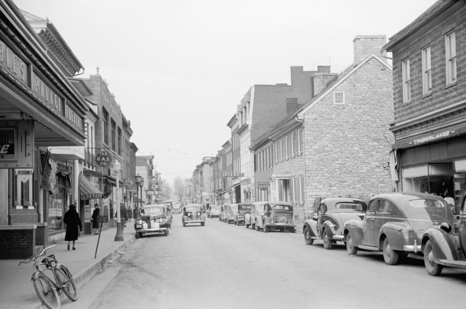 1940 black-and-white photograph of Main Street in Winchester, Virginia with storefronts, vintage cars, and pedestrians